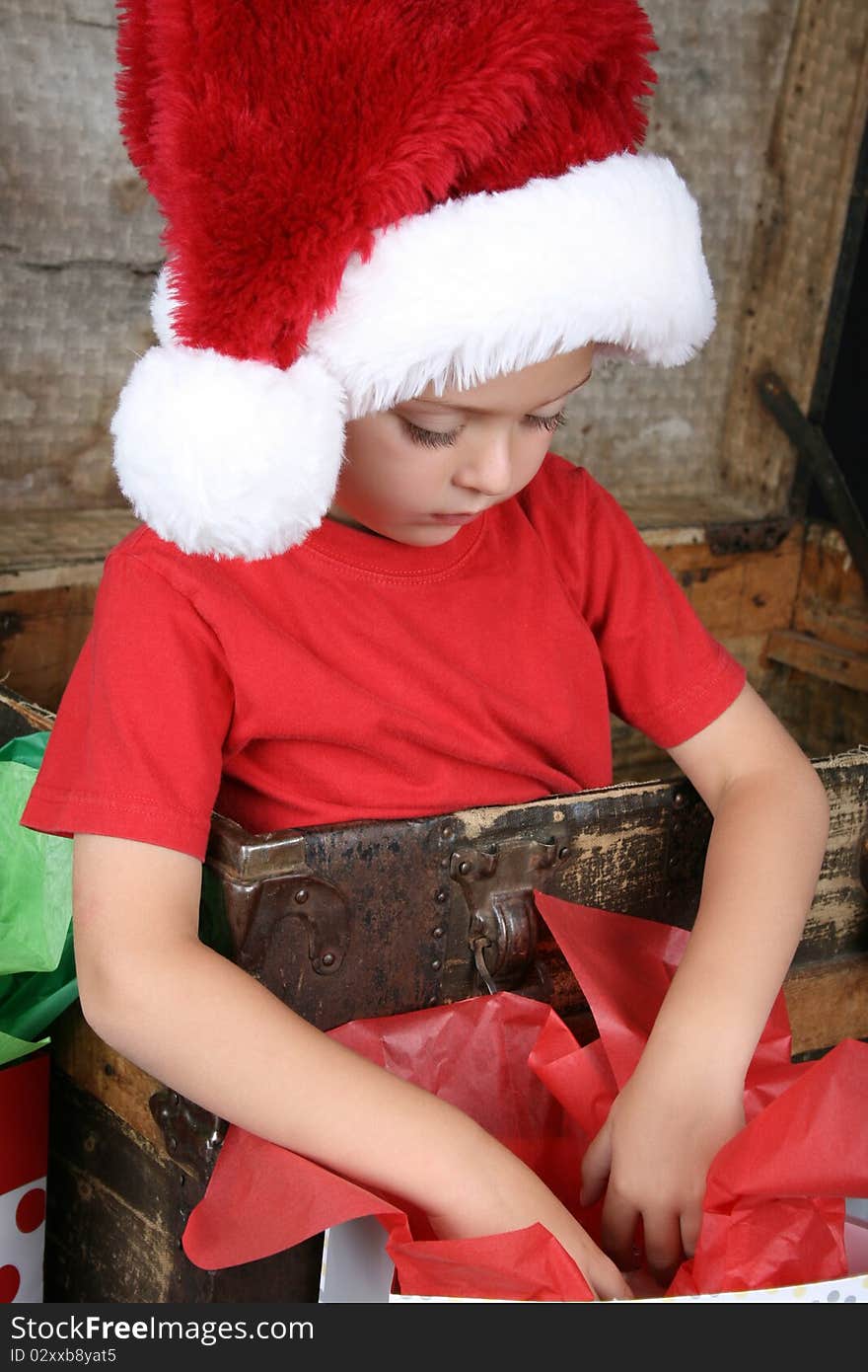 You boy wearing a christmas hat looking in his gift bag. You boy wearing a christmas hat looking in his gift bag