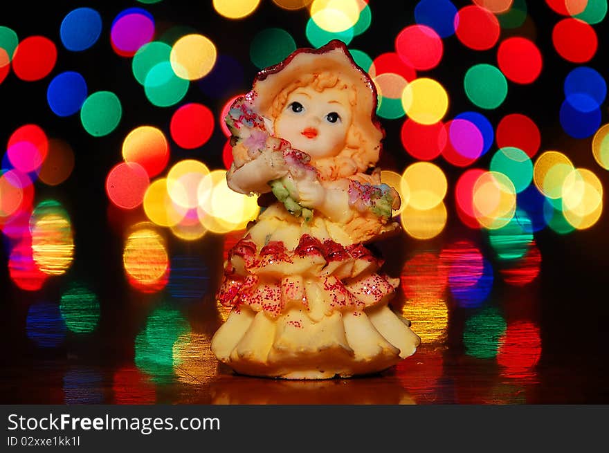 Statuette of a little girl on a background of bright lights.