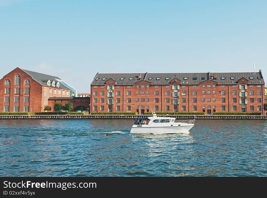 City river with tourist boat and modern buildings on the riverside