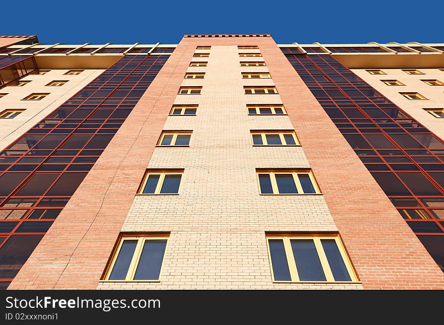 Wall of modern apartment house against a blue sky. Wall of modern apartment house against a blue sky.