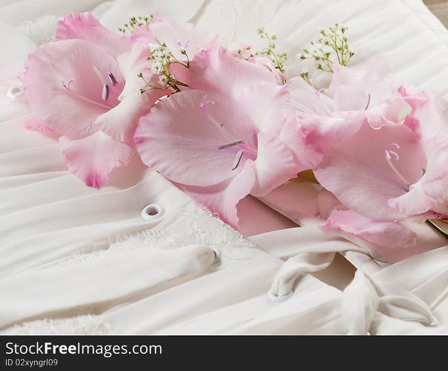 Closeup shot of wedding dress with pink flower on it. Closeup shot of wedding dress with pink flower on it