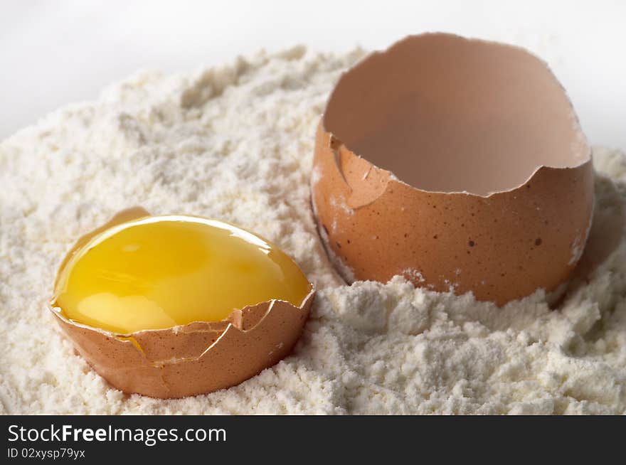 Broken eggshell and yolk in the flour macro shot. Broken eggshell and yolk in the flour macro shot