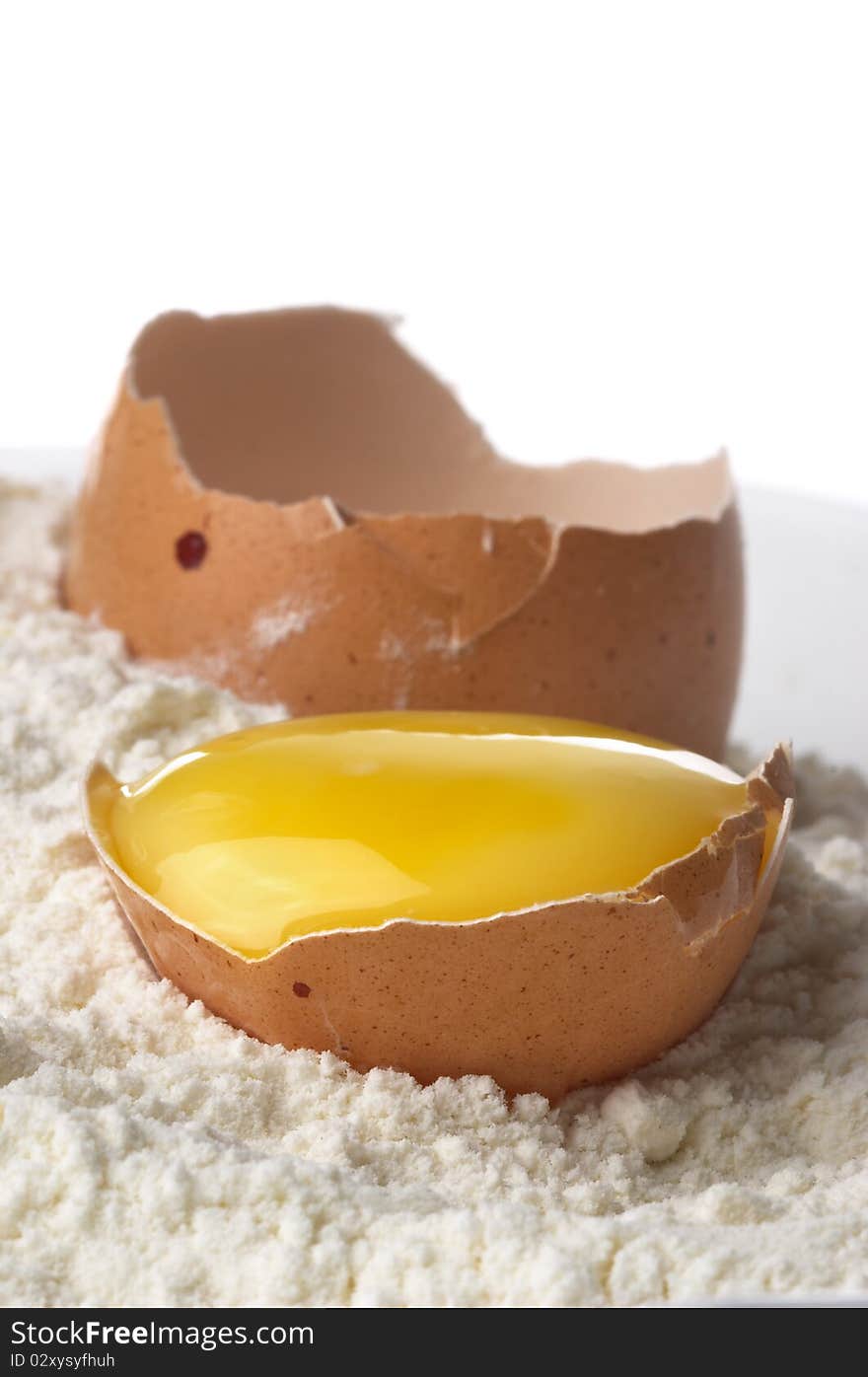 Broken eggshell and yolk in the flour macro shot. Broken eggshell and yolk in the flour macro shot