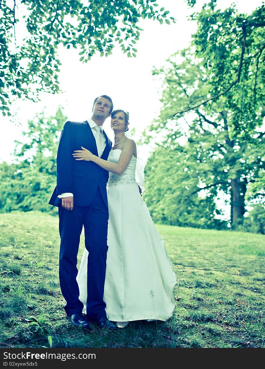 Young wedding couple - freshly wed groom and bride posing outdoors on  their wedding day. Young wedding couple - freshly wed groom and bride posing outdoors on  their wedding day