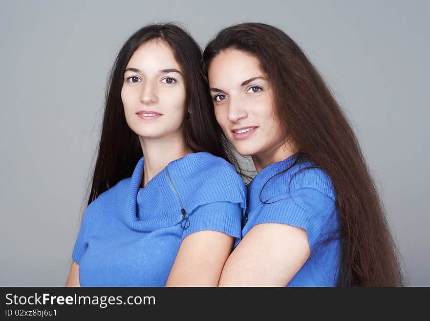 Portrait of two sisters with very long brown hair -isolated on gray