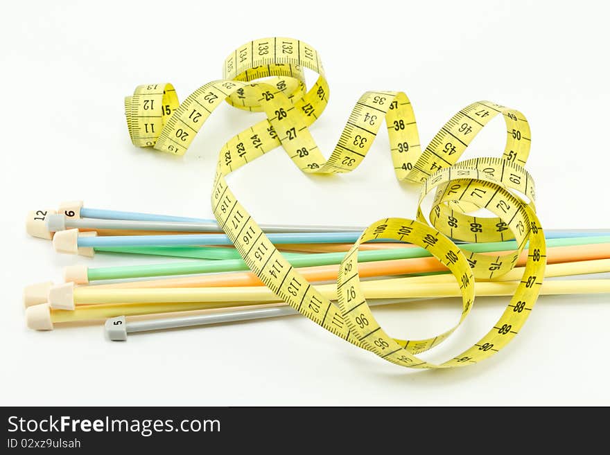 Colorful knitting needles and a yellow measuring tape