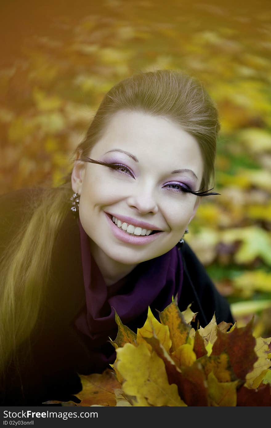 The image of a beautiful girl in a purple dress in the autumn park. The image of a beautiful girl in a purple dress in the autumn park