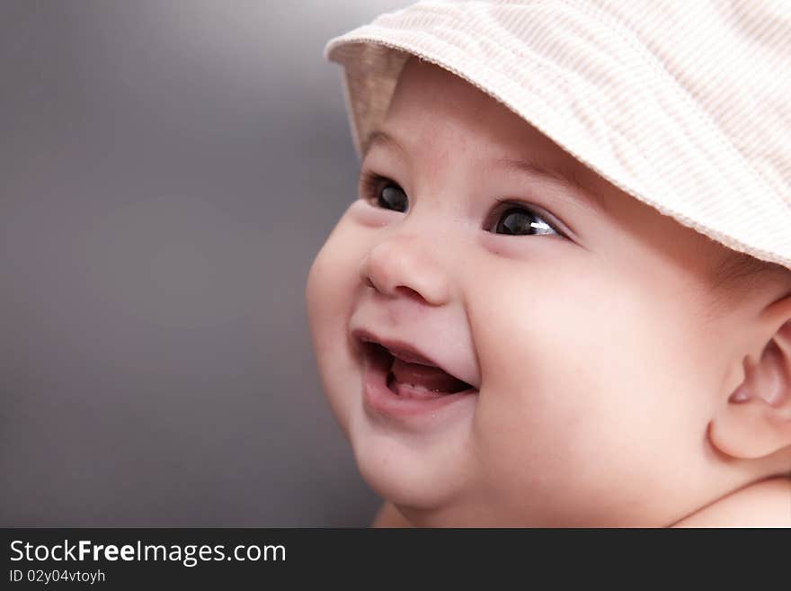 Baby smiling with hat and looking up, gray background. Baby smiling with hat and looking up, gray background