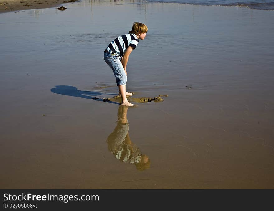 Boy at the beach in Venice with reflecting picture in wet sand