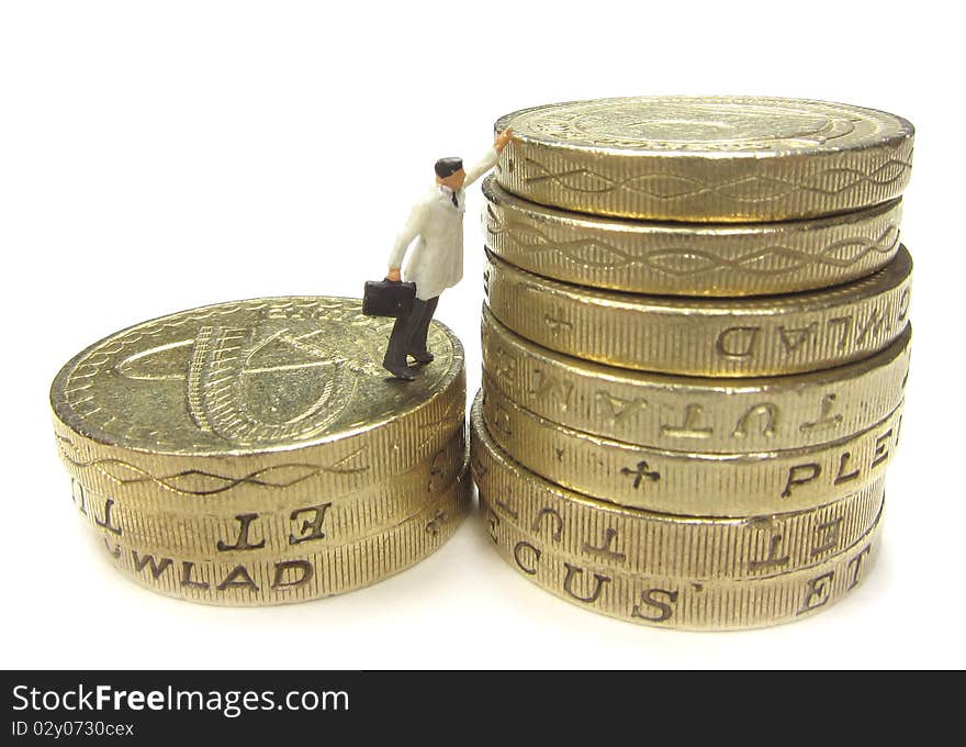 Miniature businessman reaching to the top of a stack of coins. Miniature businessman reaching to the top of a stack of coins