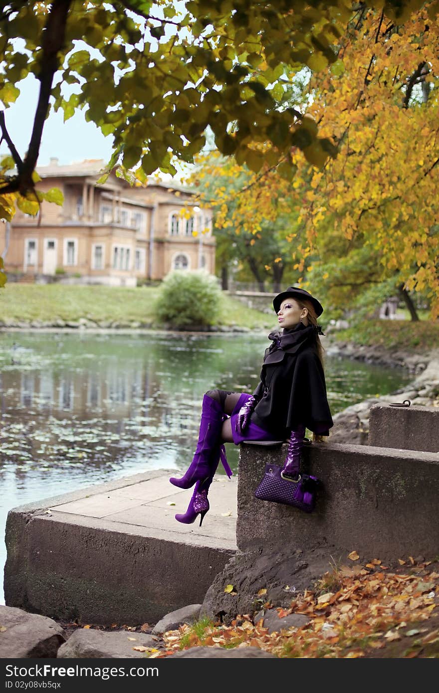 The image of a beautiful girl in a purple dress in the autumn park. The image of a beautiful girl in a purple dress in the autumn park