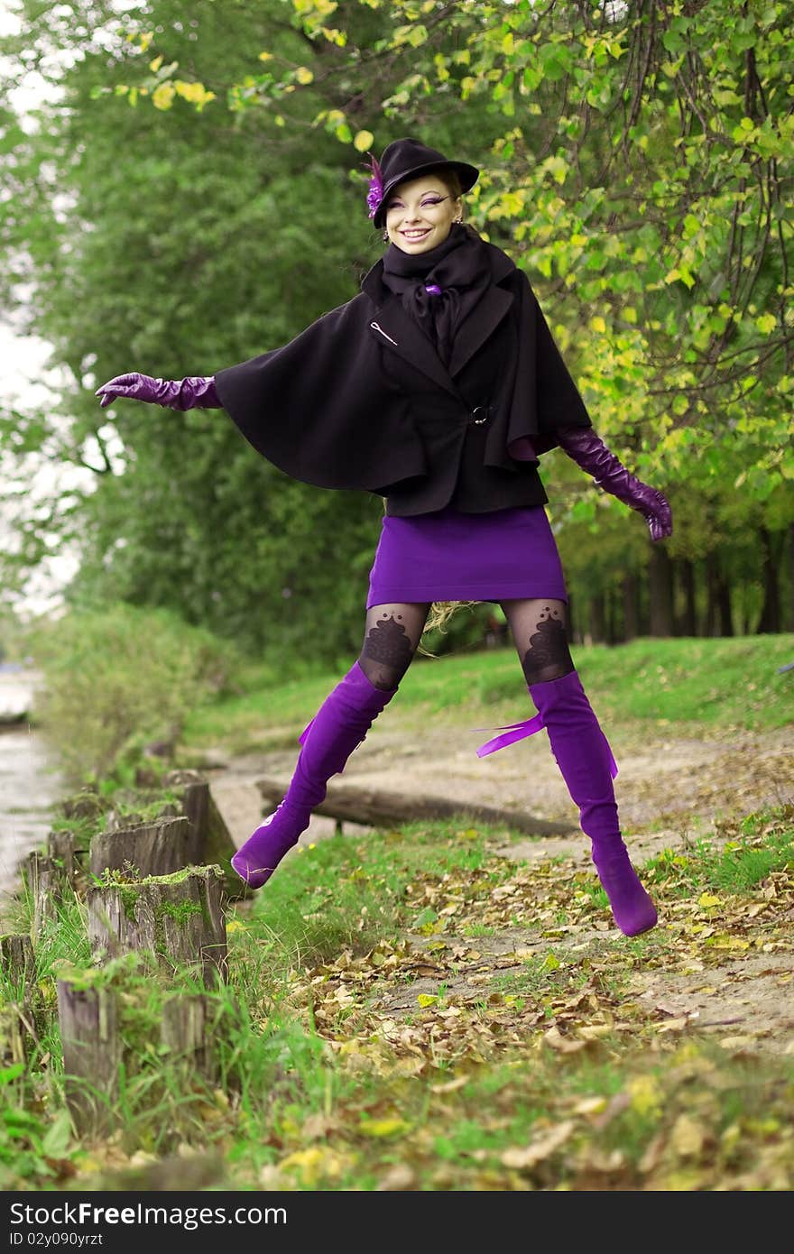 The image of a beautiful girl in a purple dress in the autumn park. The image of a beautiful girl in a purple dress in the autumn park