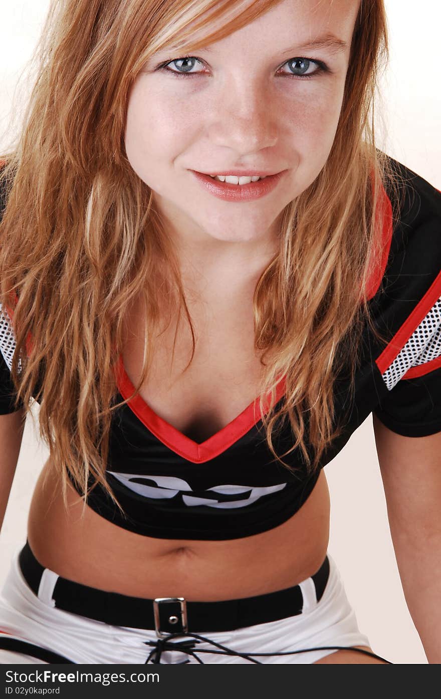 A young teenage soccer girl sitting on the floor in her uniform, in closeup, for a portrait in the studio, over white background. A young teenage soccer girl sitting on the floor in her uniform, in closeup, for a portrait in the studio, over white background.