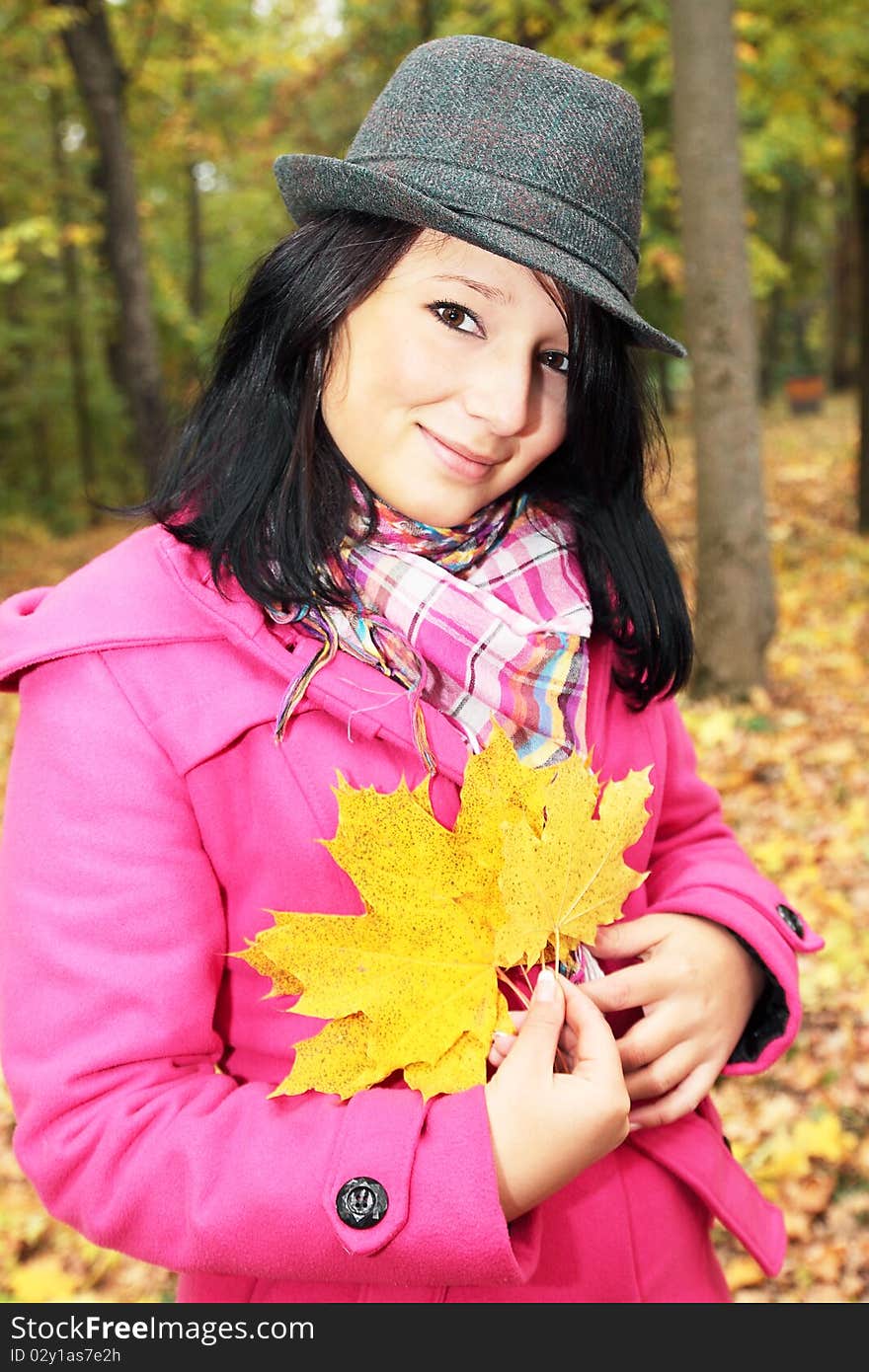 Girl in the hat holds yellow leaves