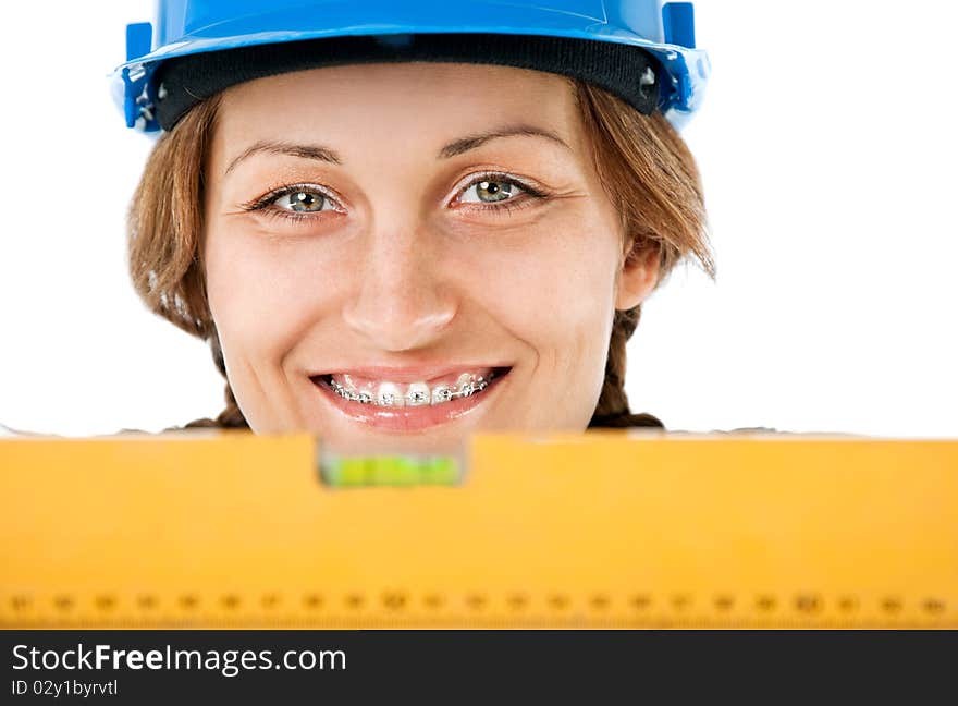 Close-up of  female worker with hardhat and braces smiling behind level. Close-up of  female worker with hardhat and braces smiling behind level