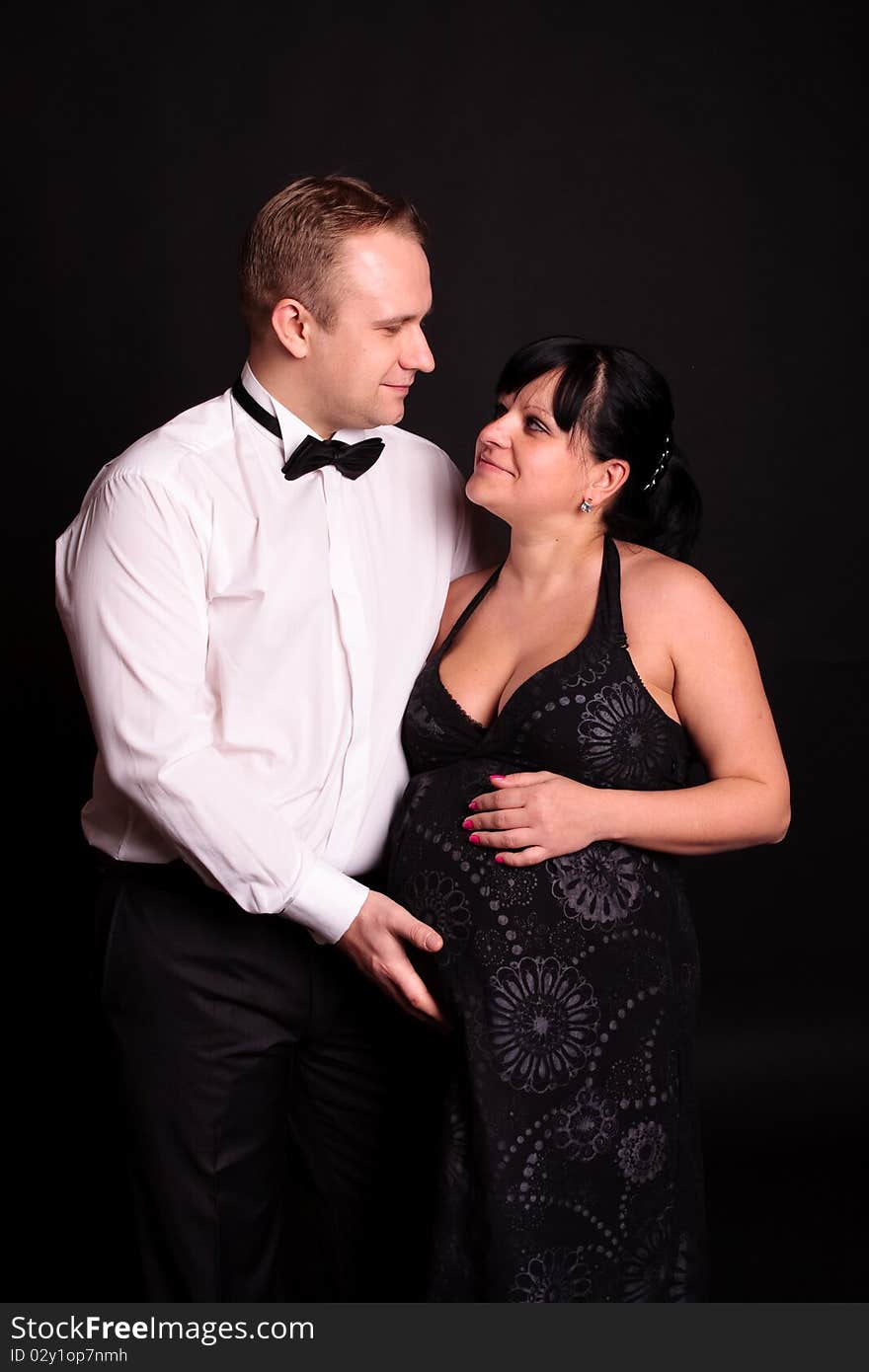 Beautiful young couple expecting their child on black background. Beautiful young couple expecting their child on black background