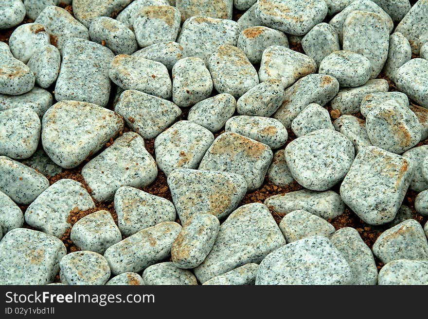 Pavement covered with round-edged, grainy, grey pebbles. Pavement covered with round-edged, grainy, grey pebbles