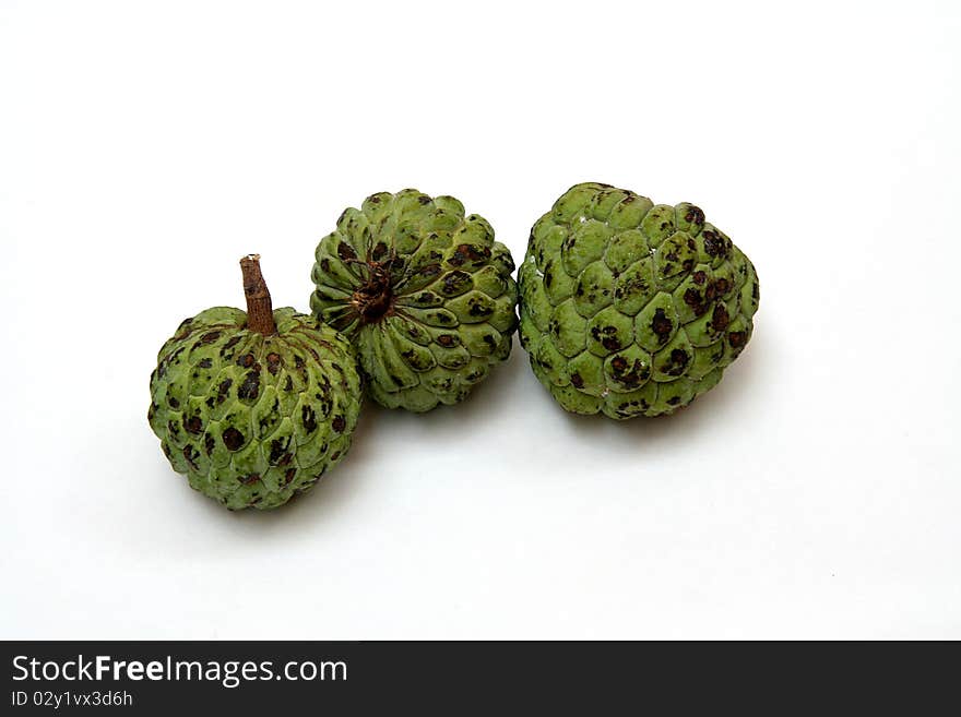 Green, scaly custard-apple fruits with long, black seeds covered with sweet, white pulp. Green, scaly custard-apple fruits with long, black seeds covered with sweet, white pulp