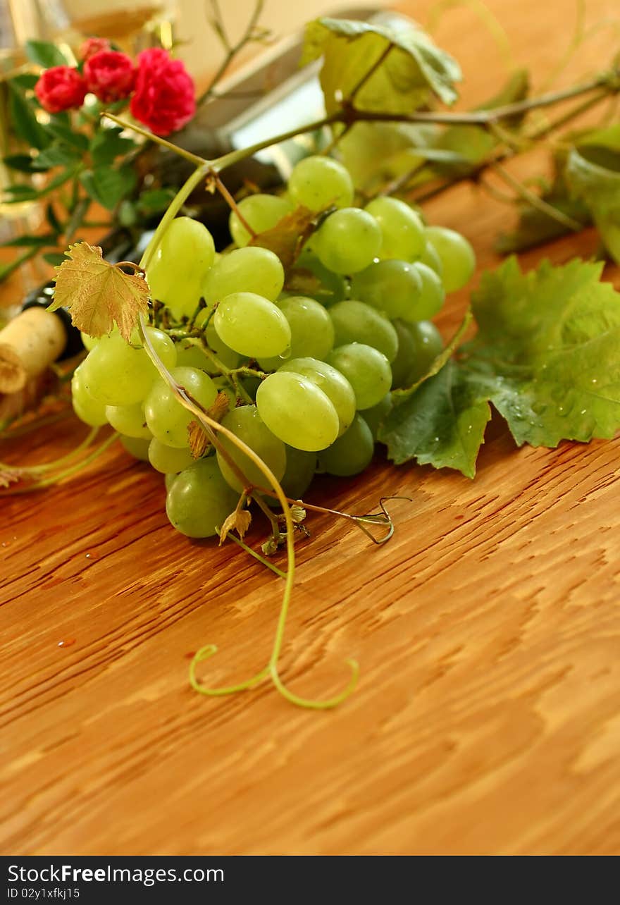 Fresh grapes, vine and vine bottle on wooden