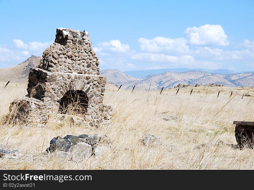 An abandoned chimney stands in the foothills of the Sierra Nevadas with that mountain range in the background. An abandoned chimney stands in the foothills of the Sierra Nevadas with that mountain range in the background.