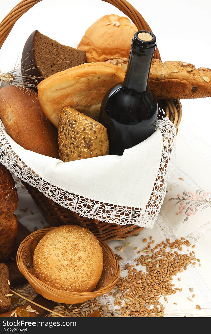 Bread products and wine in basket on white background