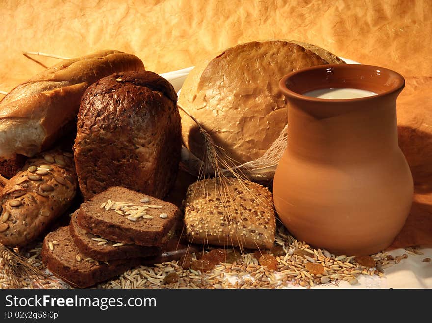 Still-life with  different bread products and jug of milk on brown classical background. Still-life with  different bread products and jug of milk on brown classical background