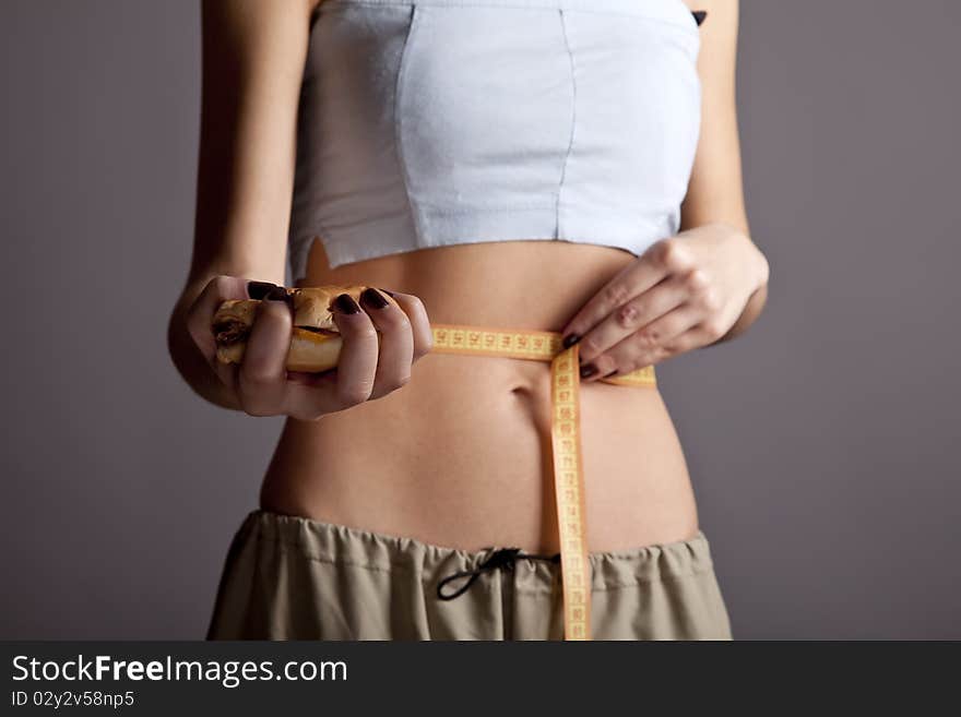 Beautiful and strong women's abs with metre nad burger. Studio shot. Beautiful and strong women's abs with metre nad burger. Studio shot.