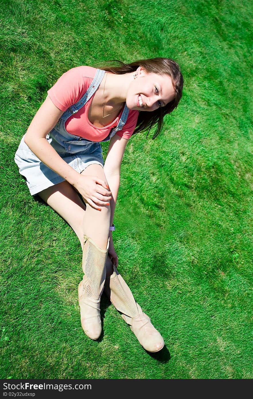 Happy young brunette on the green grass