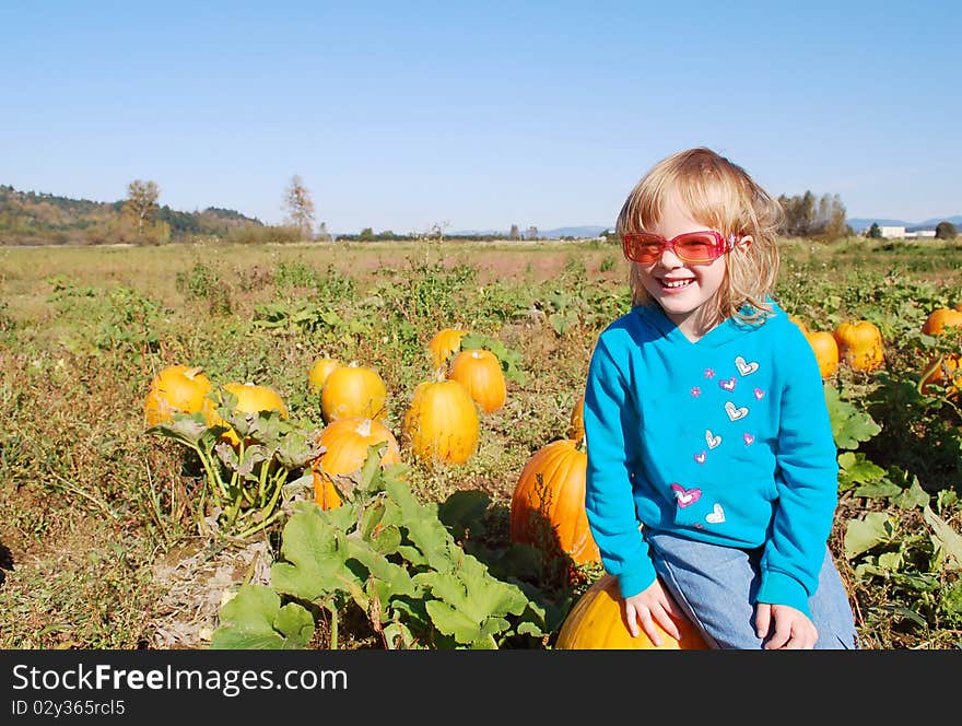 Cute Little Girl Sitting On The Pumpkin