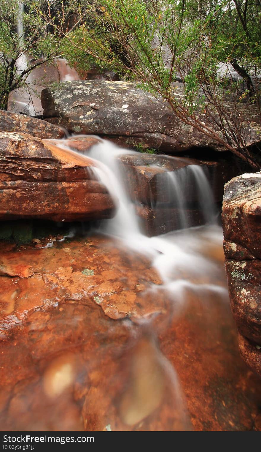 A creek cascades over some typically australian red rock. A creek cascades over some typically australian red rock