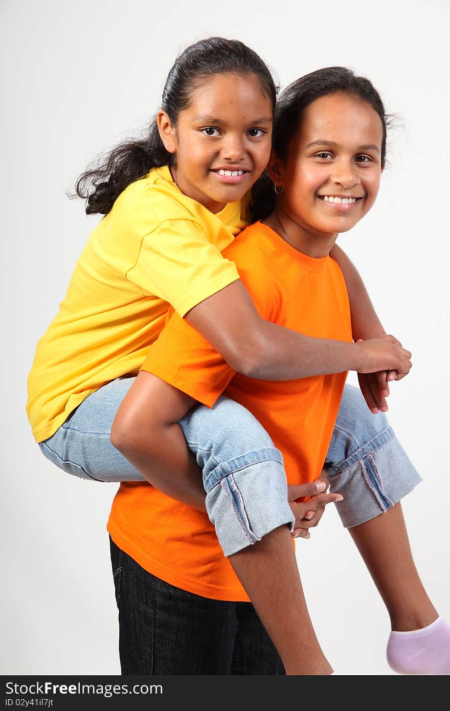 Fun piggy back ride from two happy young school girl friends together in studio - . Fun piggy back ride from two happy young school girl friends together in studio -