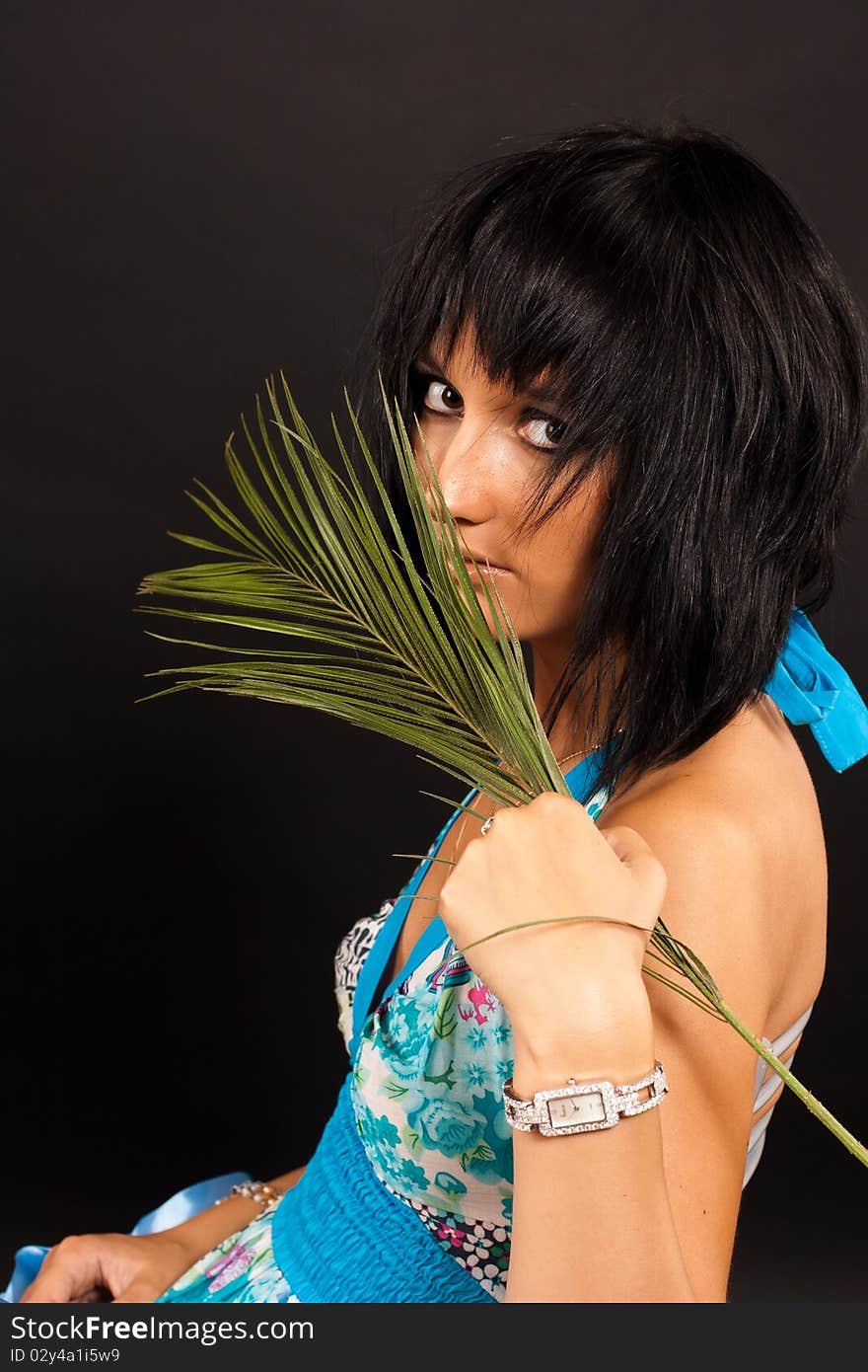 Beautiful girl holding a big green palm leaf. She is isolated on a black background. Beautiful girl holding a big green palm leaf. She is isolated on a black background.