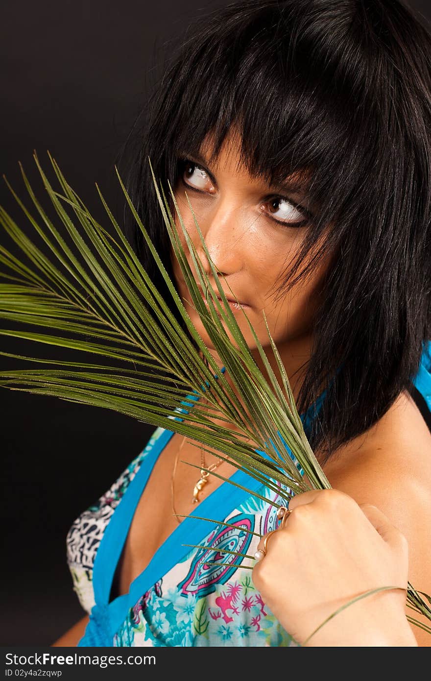 Beautiful girl holding a big green palm leaf. She is isolated on a black background. Beautiful girl holding a big green palm leaf. She is isolated on a black background.