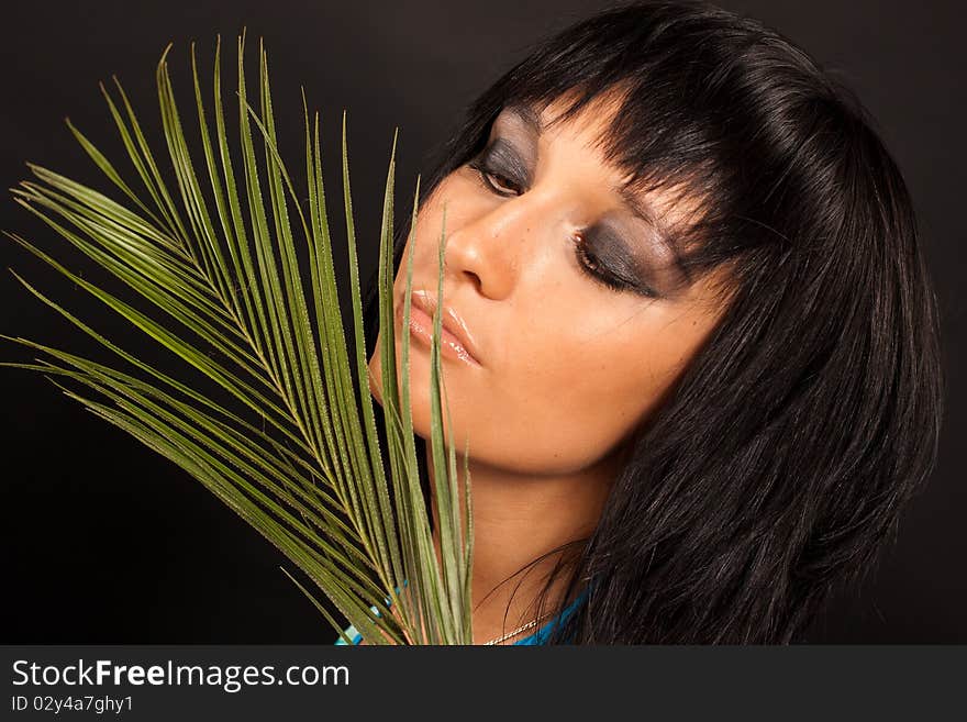 Beautiful girl holding a big green palm leaf. She is isolated on a black background. Beautiful girl holding a big green palm leaf. She is isolated on a black background.