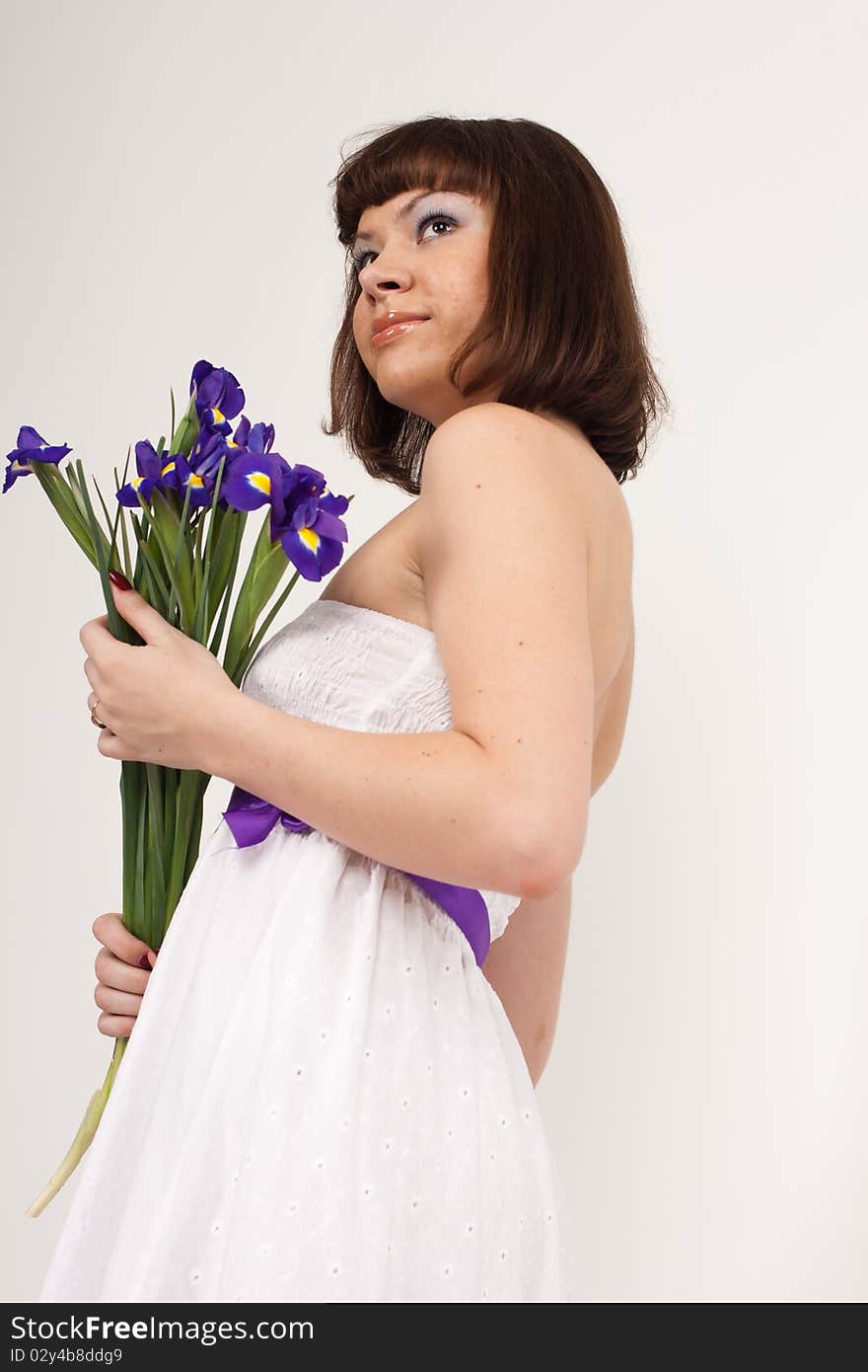 Beautiful girl holding a bouquet of irises. She is in studio isolated on a white background. Beautiful girl holding a bouquet of irises. She is in studio isolated on a white background