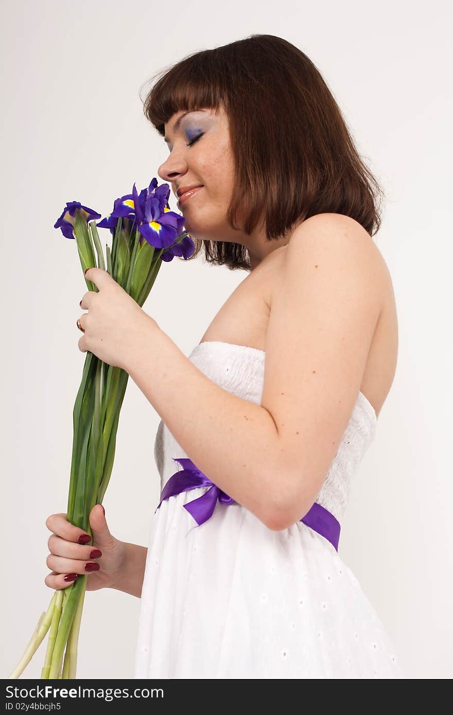 Beautiful girl holding a bouquet of irises. She is in studio isolated on a white background. Beautiful girl holding a bouquet of irises. She is in studio isolated on a white background