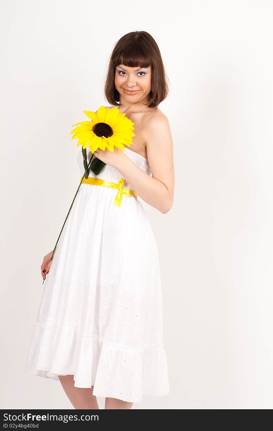 Beautiful girl smiling and holding a sunflower - isolated over a white background. Beautiful girl smiling and holding a sunflower - isolated over a white background