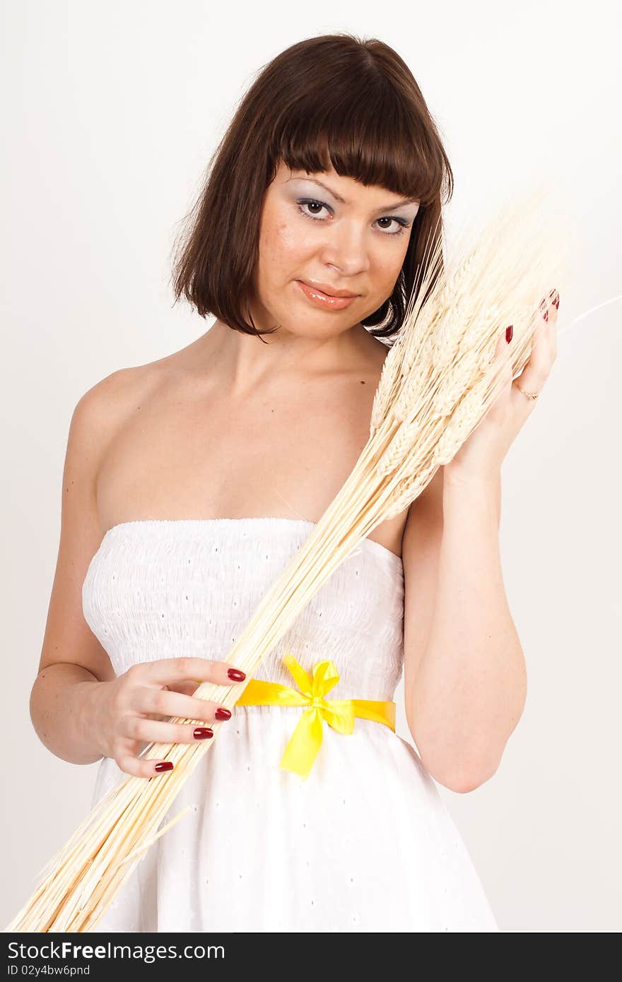 Beautiful brunette girl in white dress with ears of wheat in her hair isolated on the white background. Beautiful brunette girl in white dress with ears of wheat in her hair isolated on the white background