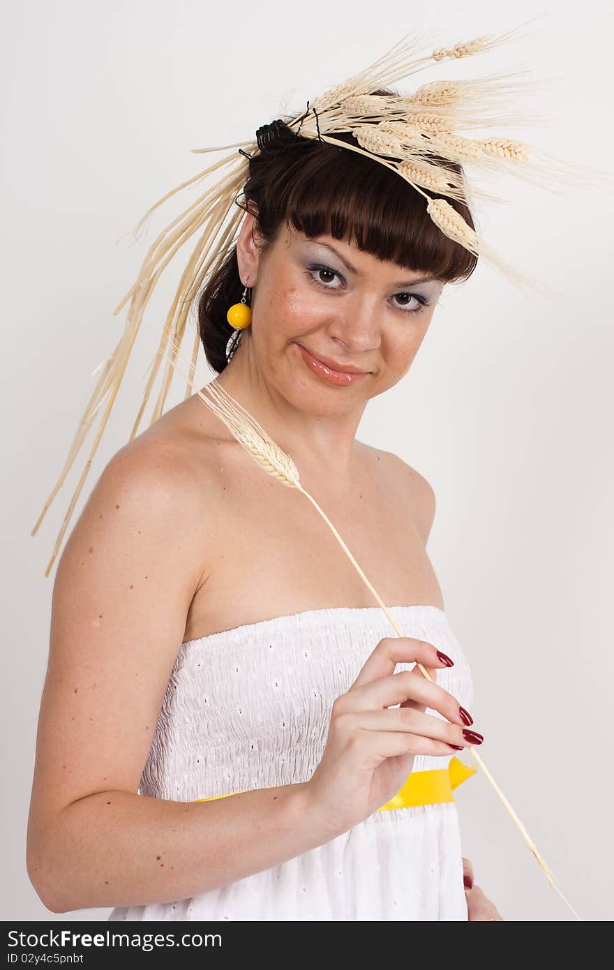 Beautiful brunette girl with ears of wheat in her hair isolated on the white background