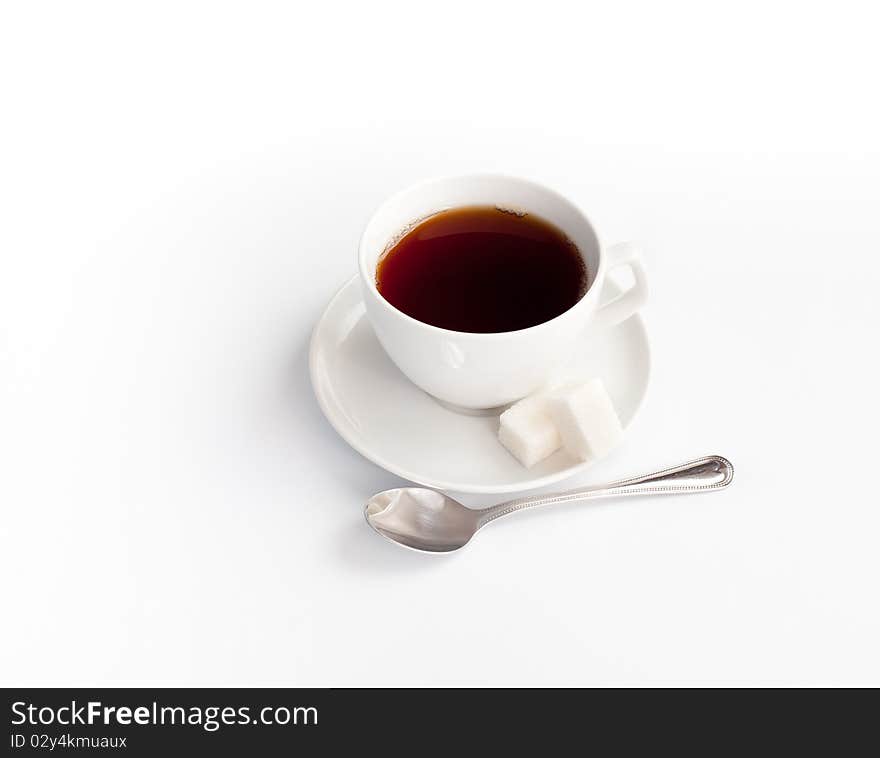 Cup of tea with sugar and spoon isolated on white