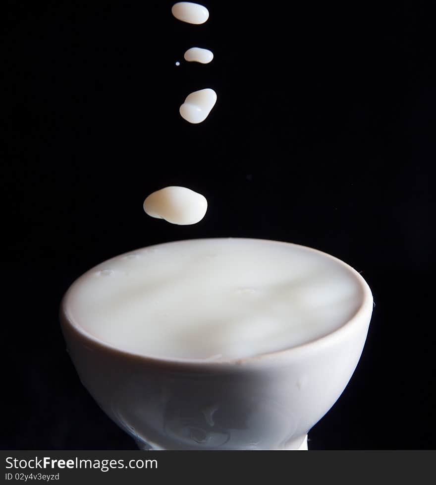 Splash milk in the glass on the black background