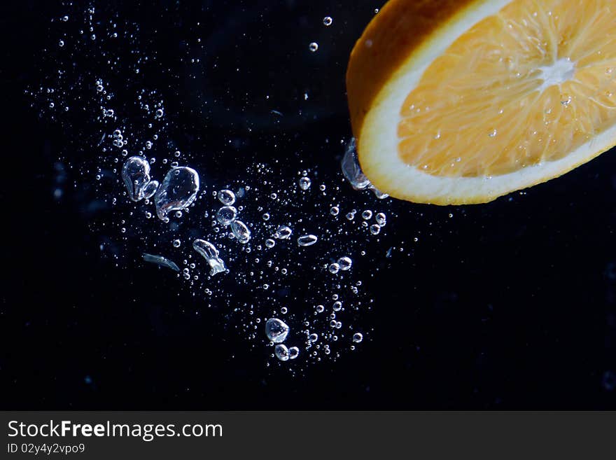 Orange and splash water over black background