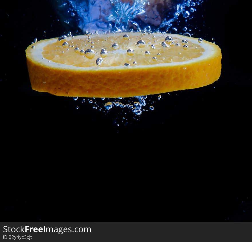 Orange and splash water over black background