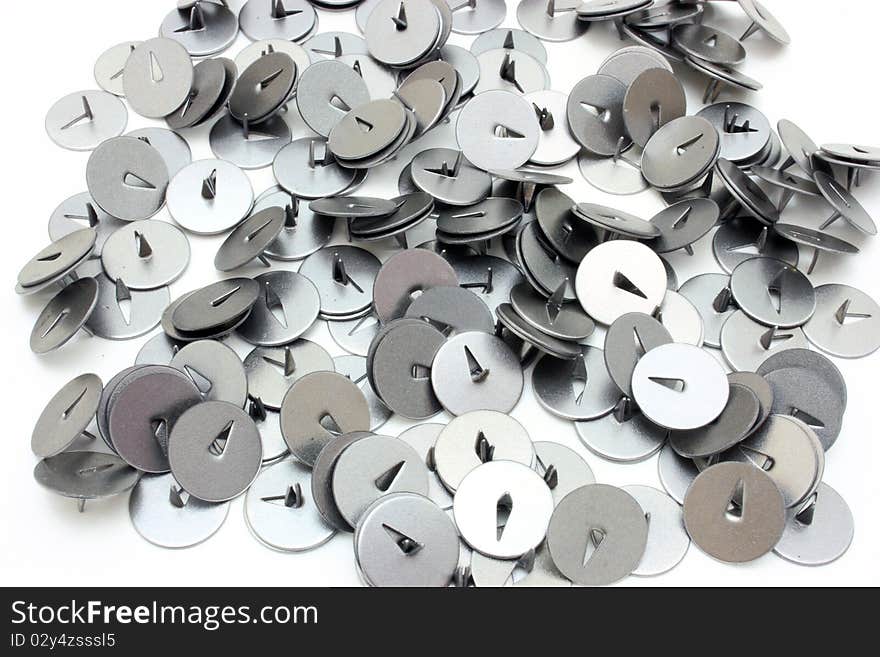 On a table there is a heap of buttons for a paper. They metal and sharp.