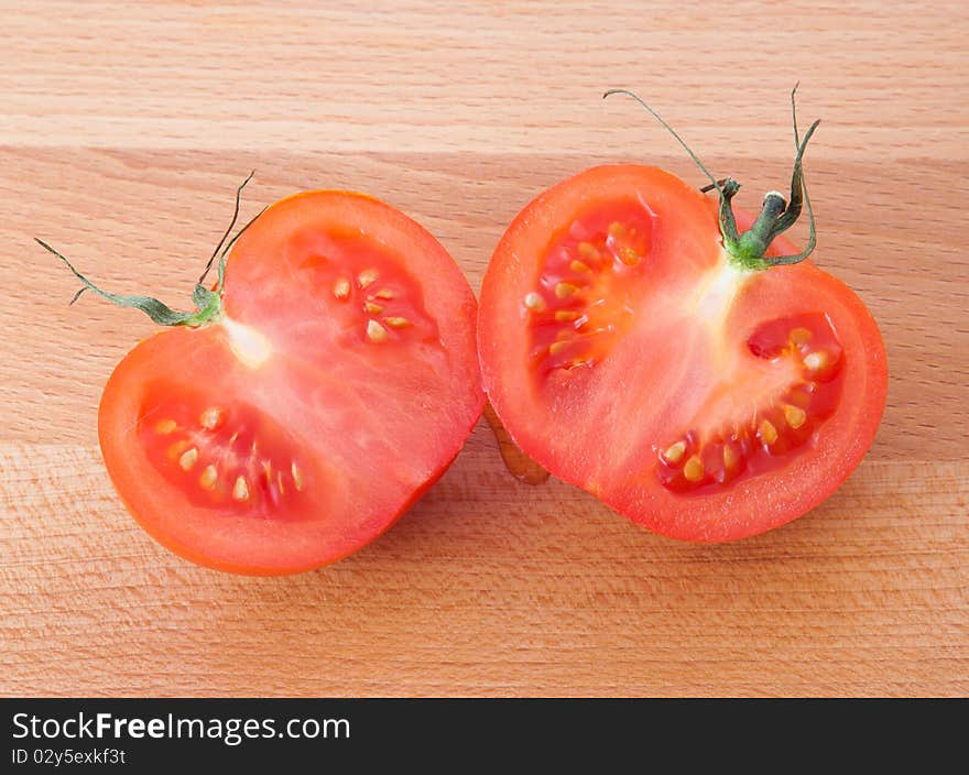 Two part of tomato on brown kitchen board. Horizontal image