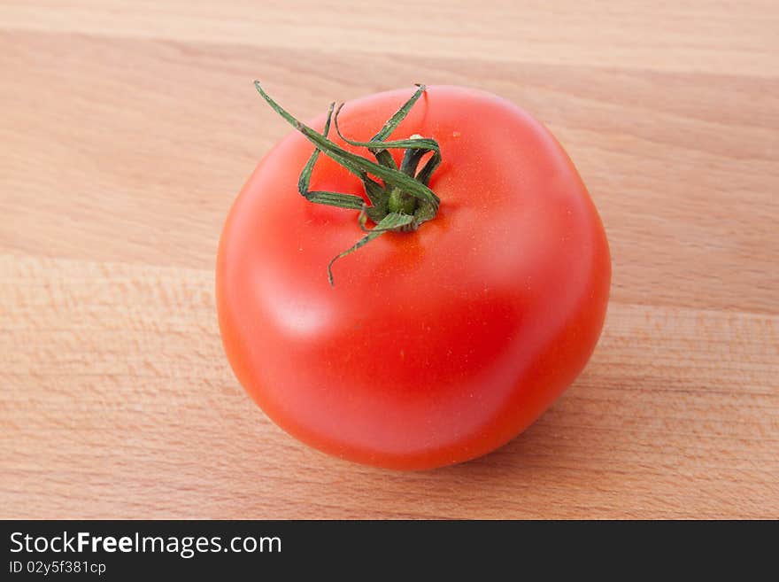 Red tomato on brown kitchen board. Horizontal image