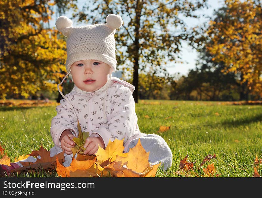 Baby with maple leaf playing in the park. Baby with maple leaf playing in the park