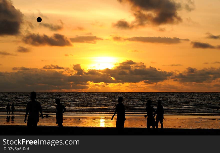 Football players playing under the sunset at the beach. Football players playing under the sunset at the beach