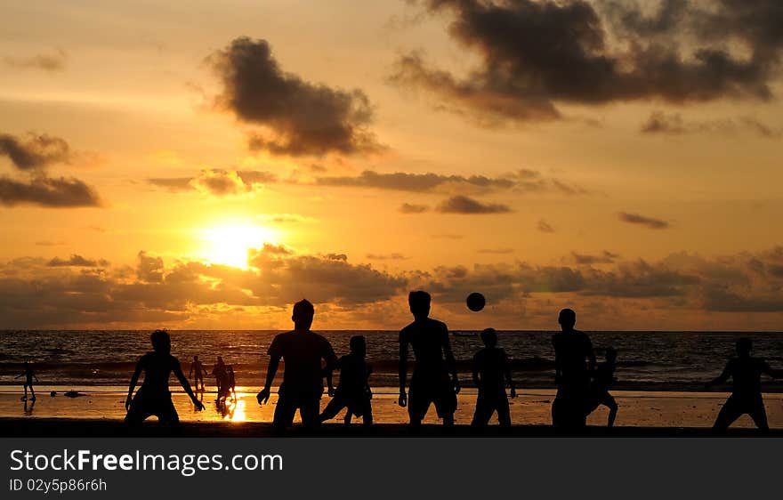 Football players playing under the sunset at the beach. Football players playing under the sunset at the beach