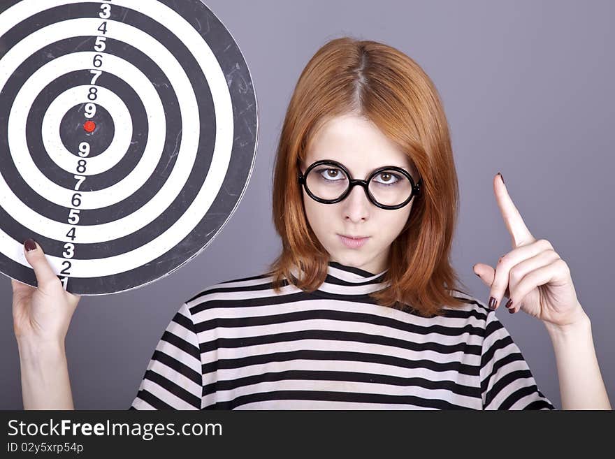 Red-haired girl with dartboard. Studio shot.